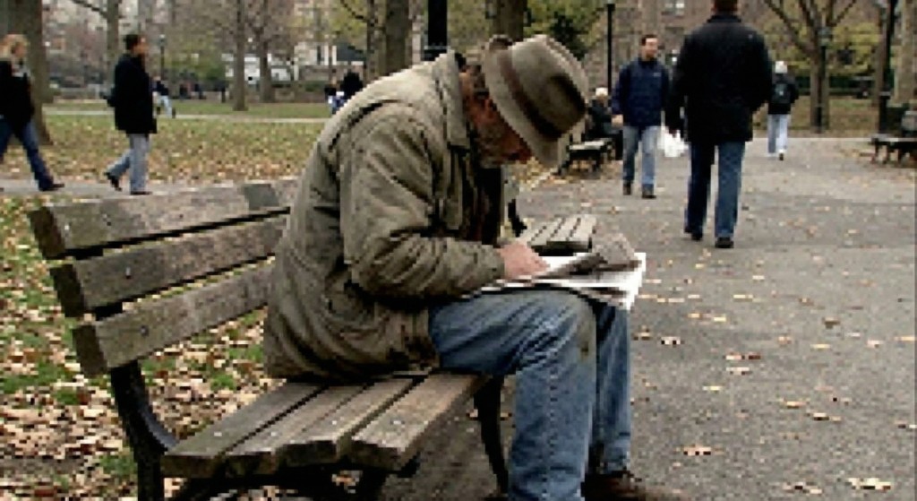 Man in his forties sitting on a park bench reading in a calm setting